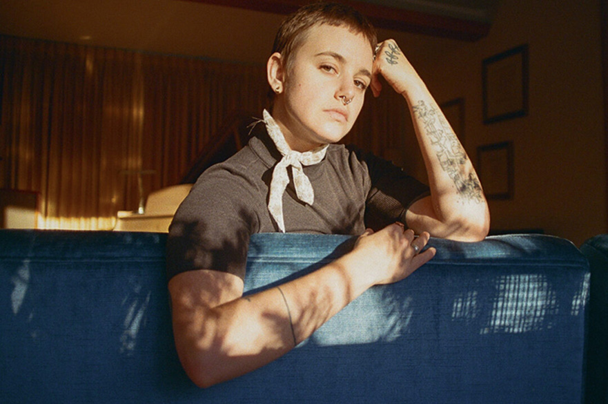 A woman with short hair sat on a blue sofa facing behind it.