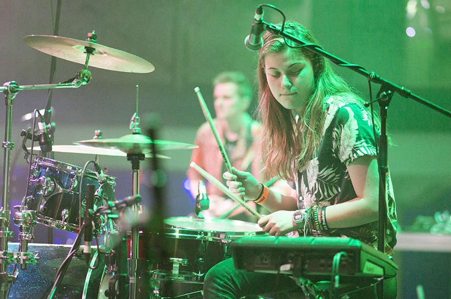 A girl playing the drum kit on stage.