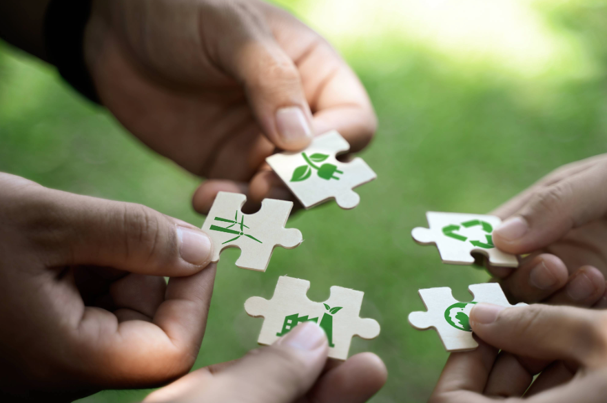 People holding puzzle pieces with images on representing sustainability
