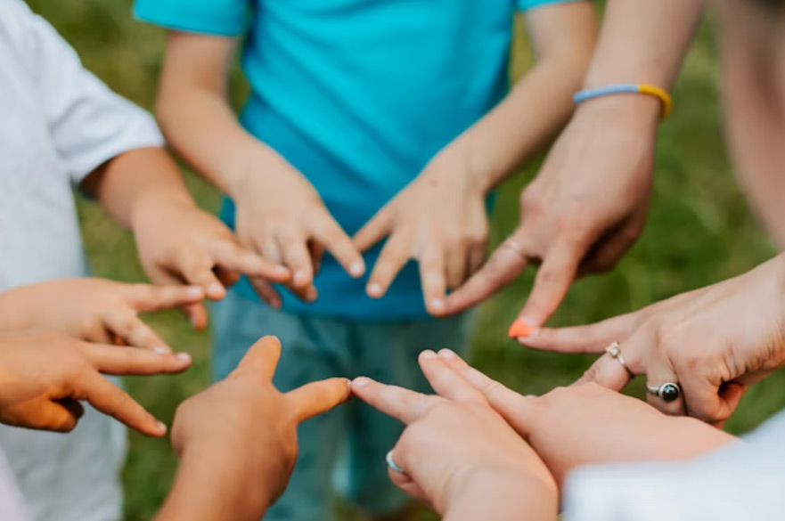 A star shape made up of four children and an adult making peace symbols with their hands.