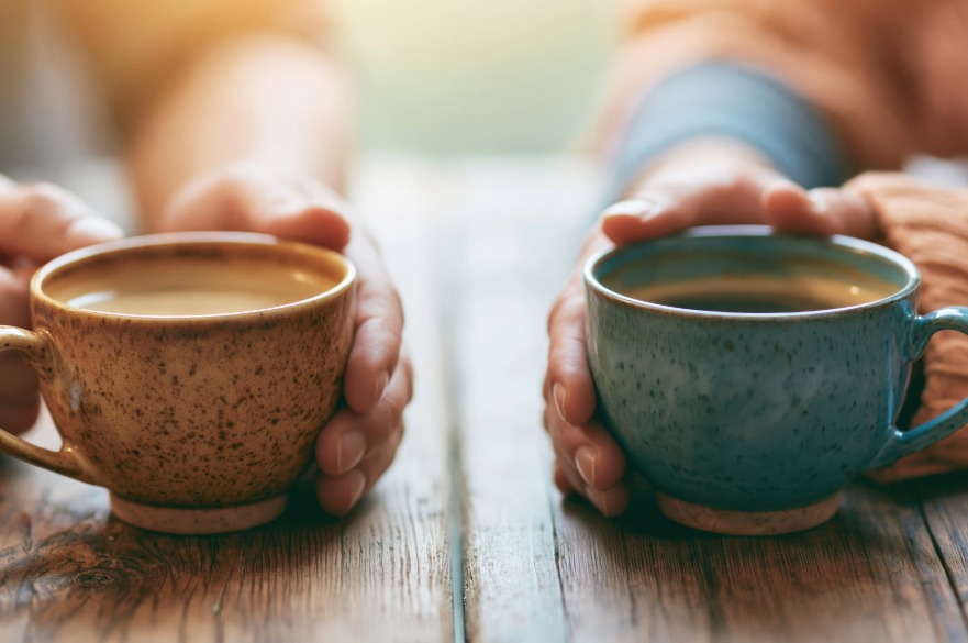 Two hands holding mugs of coffee