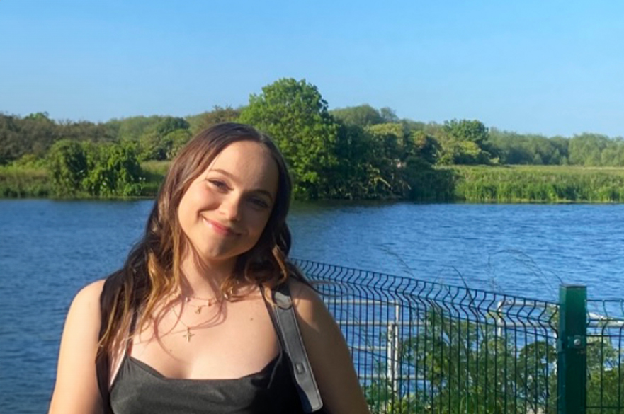 Roksi smiling at the camera next to a lake