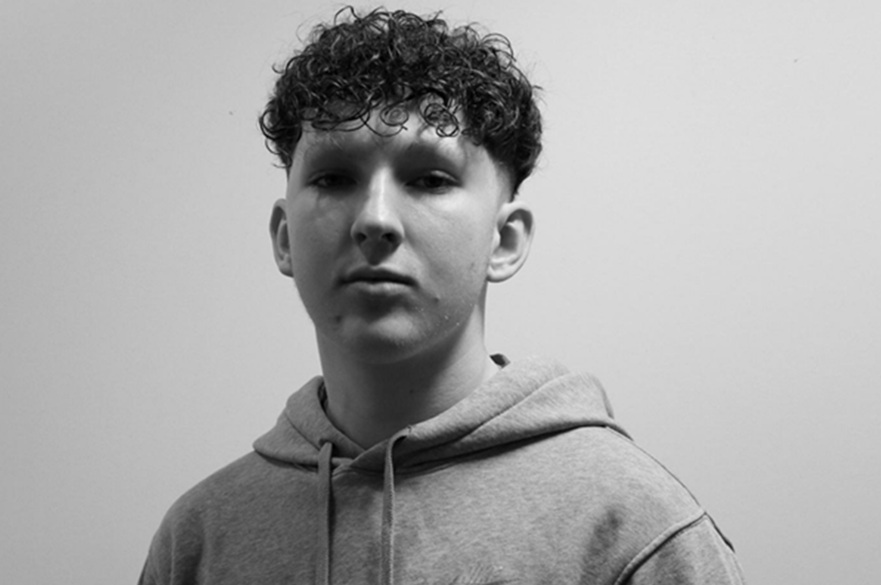Olly Lendrum profile A black and white picture of a person that is facing the camera, posed for a photograph.