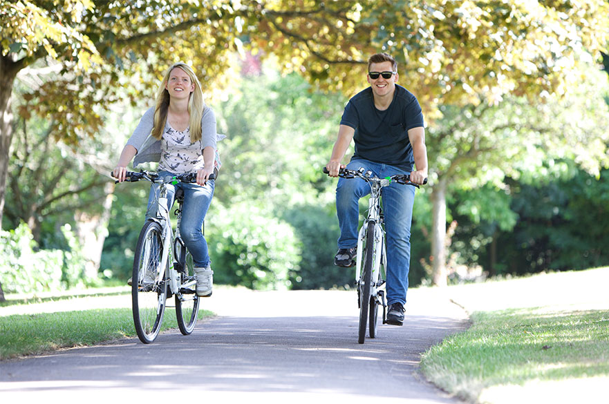 Two students cycling through a park