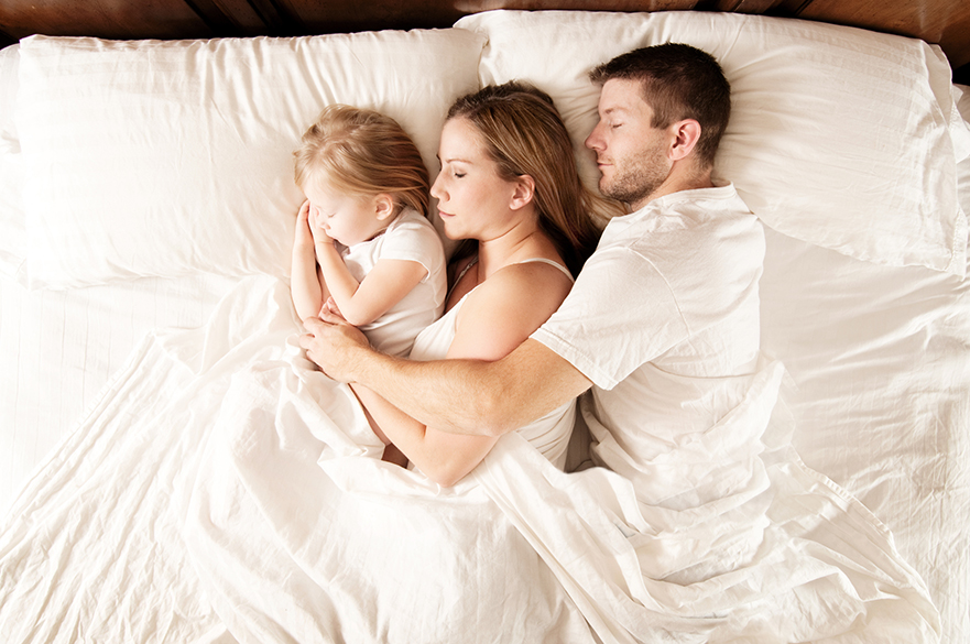 Family sleeping in a bed