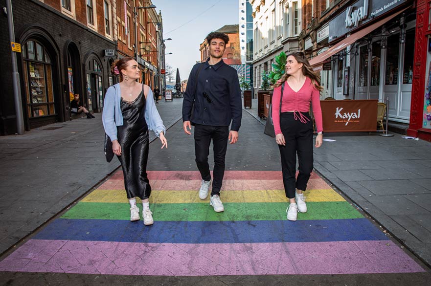 people walking on road marked like a rainbow