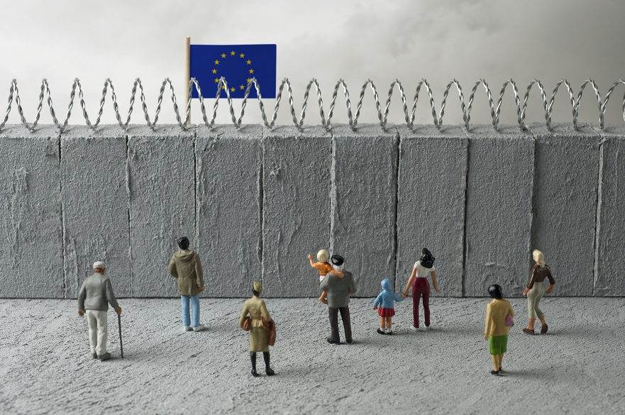 European Union refugee crisis concept. People in front of a border wall with a EU flag