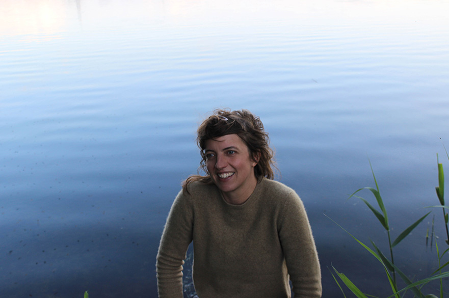A women smiling in front of a lake.