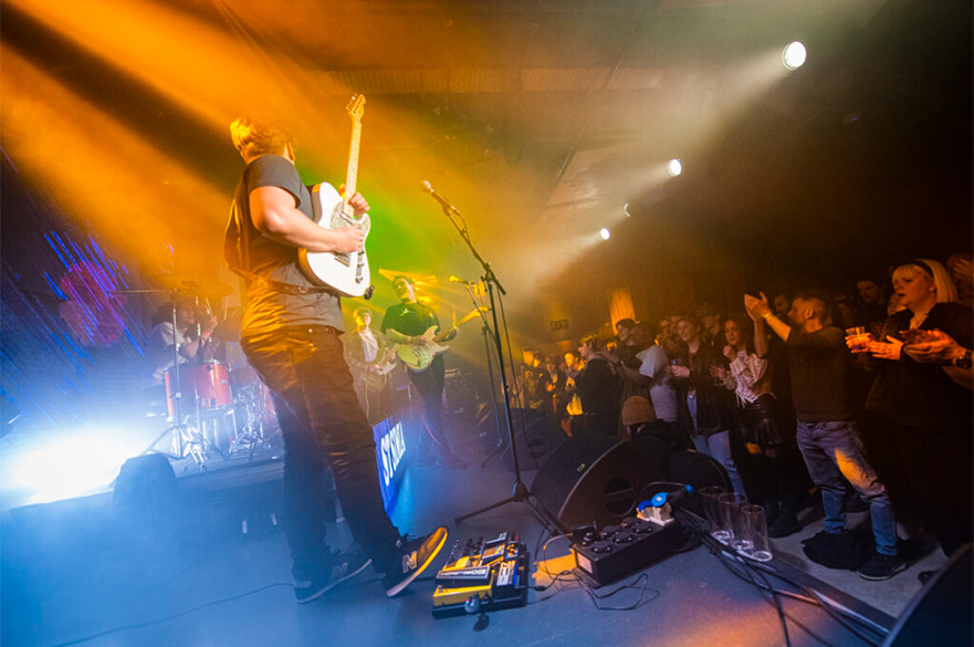 A band performing in front of an audience on the Metronome stage.