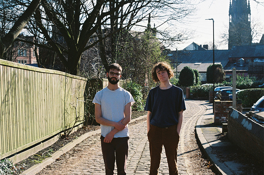 Two men stood in a street looking at the camera.
