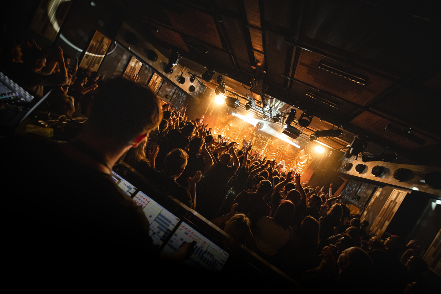 Person standing  behind a sound desk with a crowd in the background