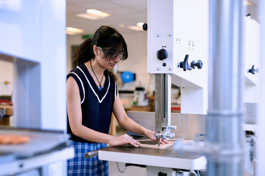 Student wearing PPE using Bandsaw