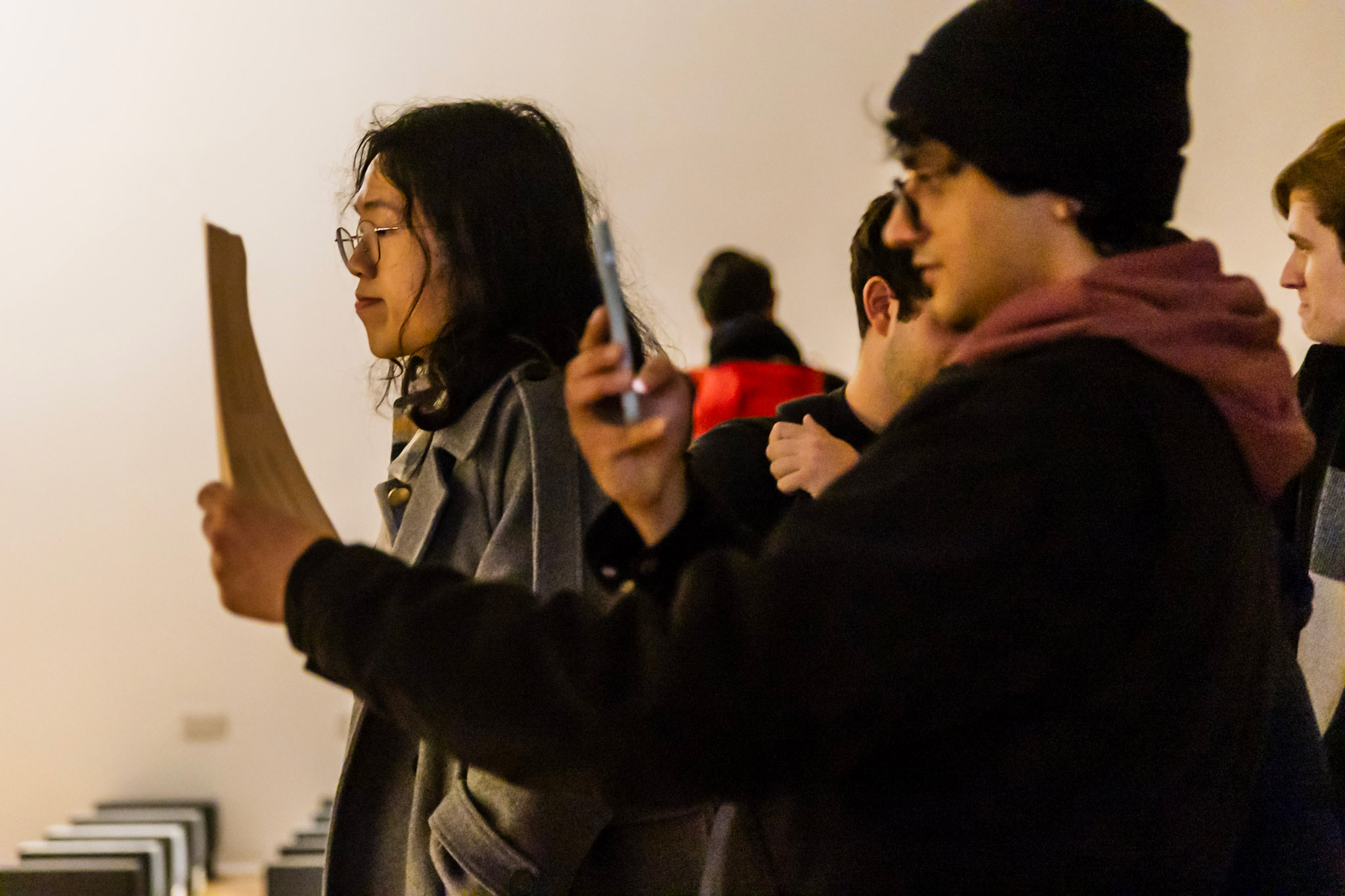 A white man in focus taking pictures at an art gallery exhibition.