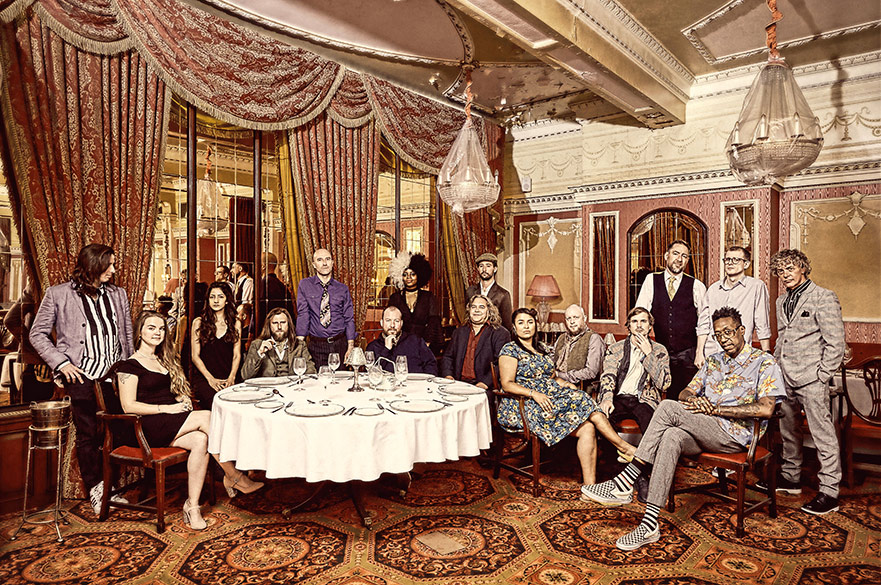 The Invisible Orchestra sat and stood around a table in a grand hotel.