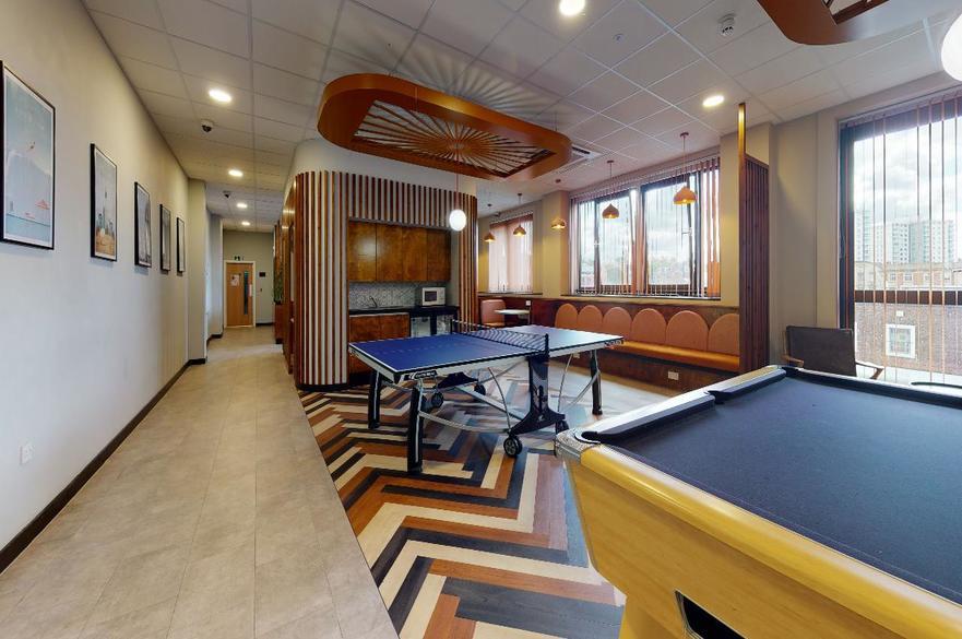 Social area with a pool and ping pong tables in the middle of the room image