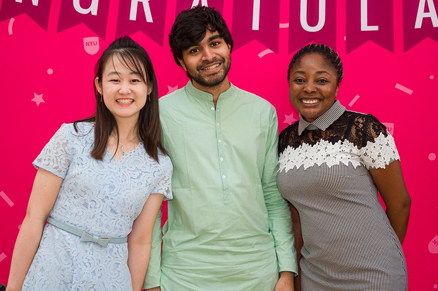 Three students in front of banner