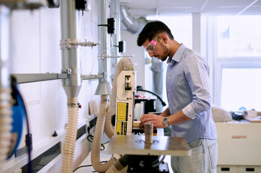 Student wearing PPE using sanding machine