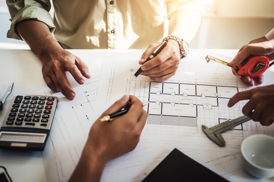 Workers drawing up some construction plans at a desk