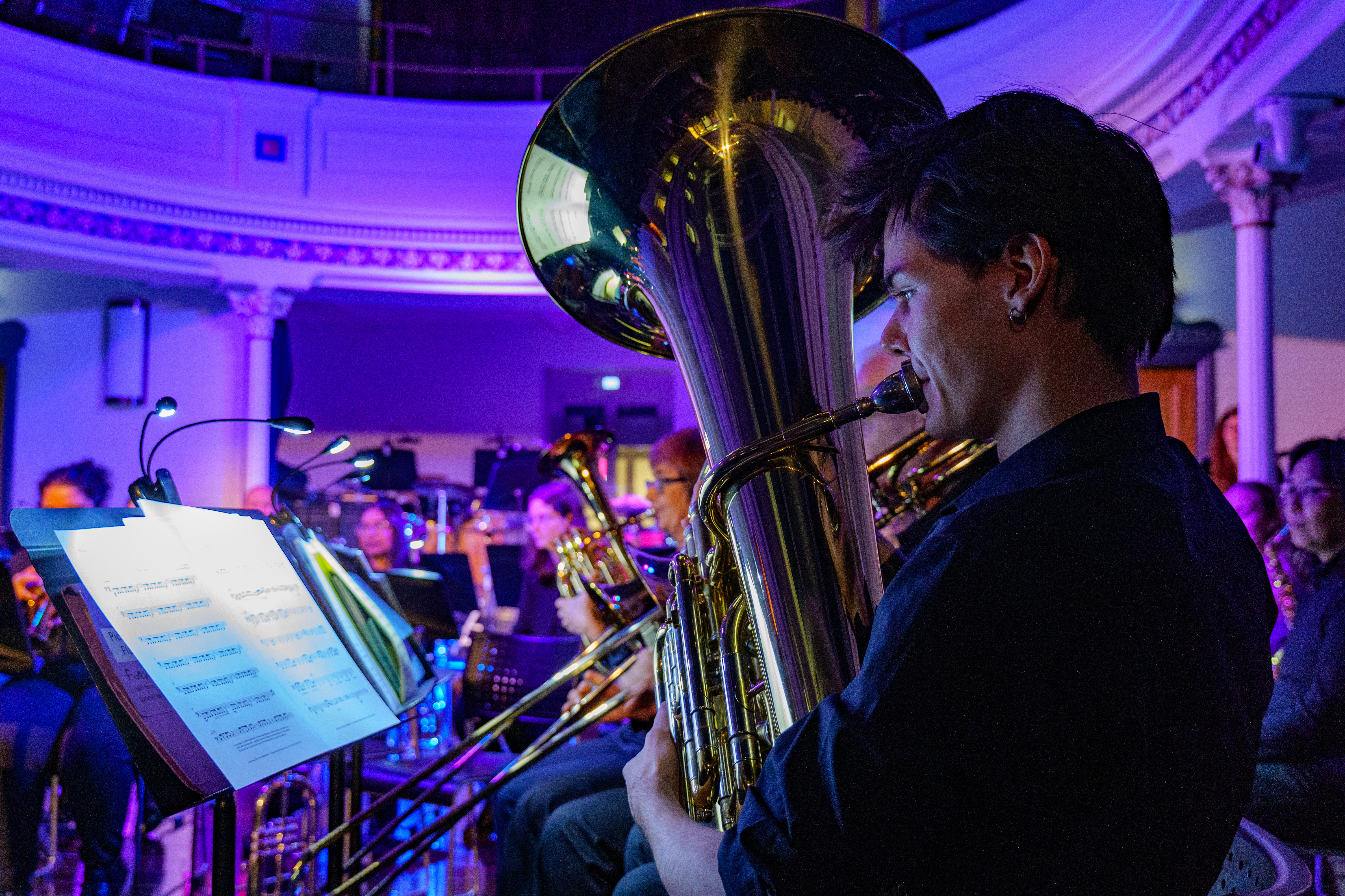 A male member of the NTU Brass Ensemble playing a flugelhorn.