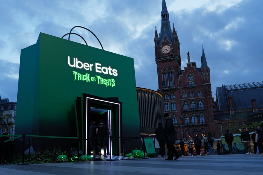 An advertising display installation of a giant Uber grocery bag with Trick or Treat written on it. The giant bag is in a public outside area of London and people are walking about.