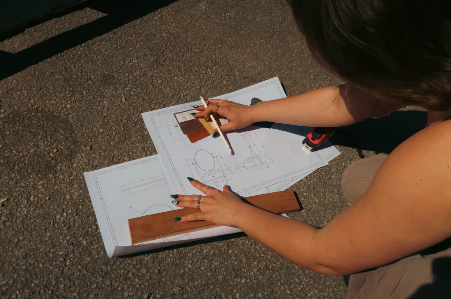 A person crouching, drawing design plans on the floor.