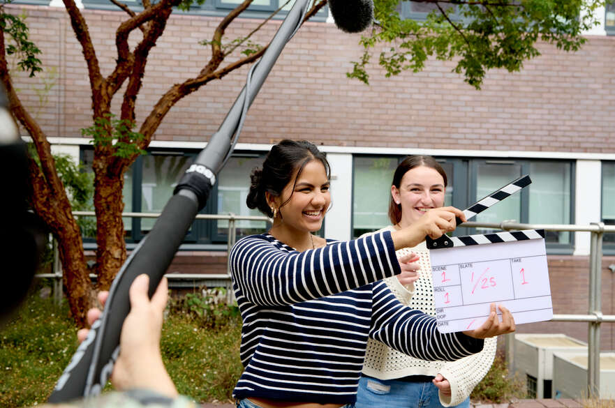 Three students filming a scene using filming equipment