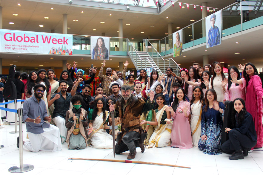 Robin Hood kneels at the front of a crowd of students celebrating Global Week