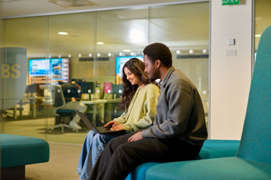 Two students sitting on a sofa with a laptop on their lap