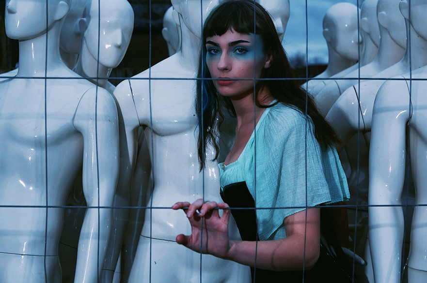 Chloe Rodger's stood inside a cage in front of mannequins. 