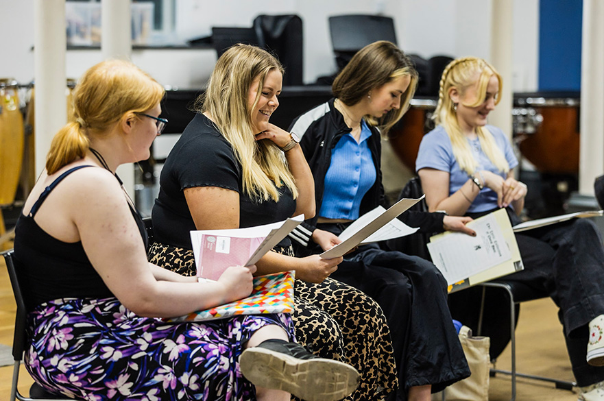 Three women rehearsing in a practice room.