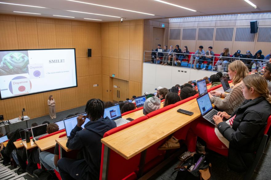 Students in a lecture theatre watching a woman speak