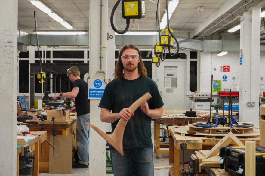 A person in a woodworking workshop, standing, posed for a photograph.