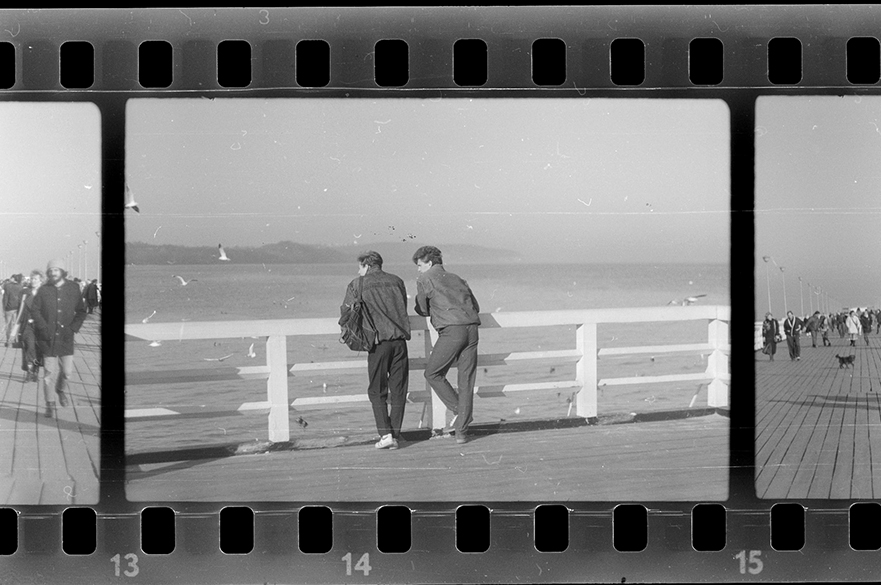 Photography negatives of two men looking over a railing.