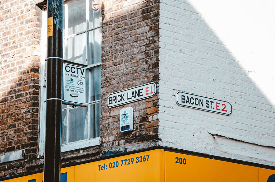 Street signs at the corner of Brick Lane and Bacon Street