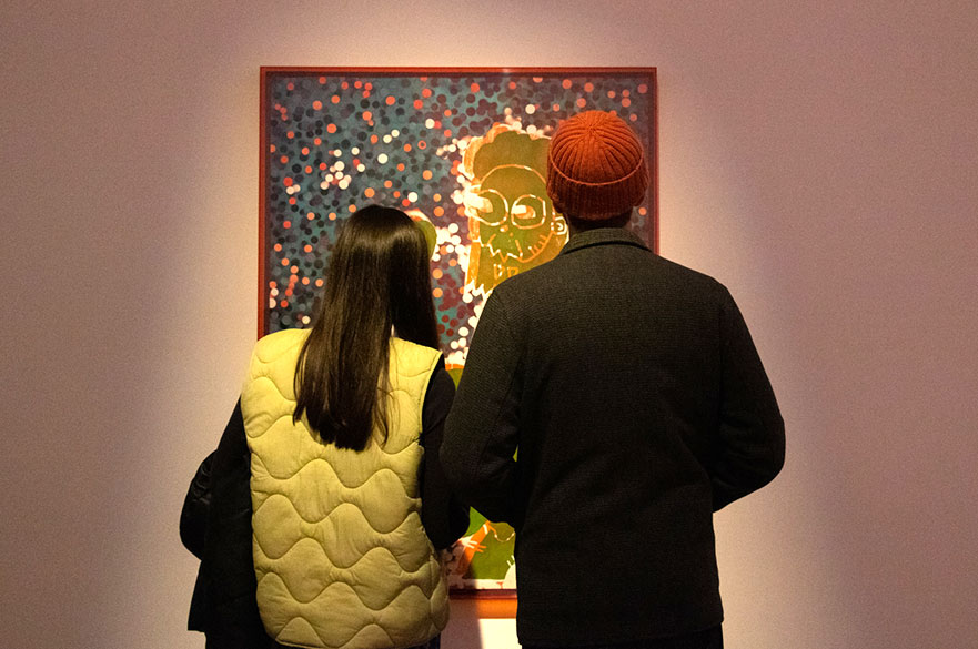 Two people looking at artwork on a wall.