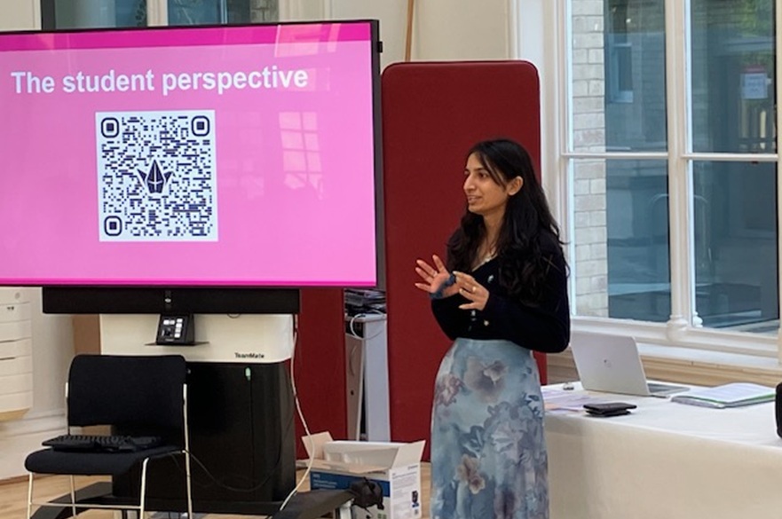 A student presenting in front of a television screen.