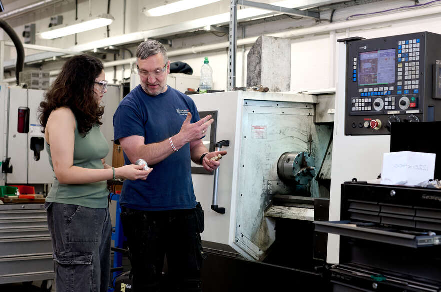 Student and technician looking at Ajax part CNC machine