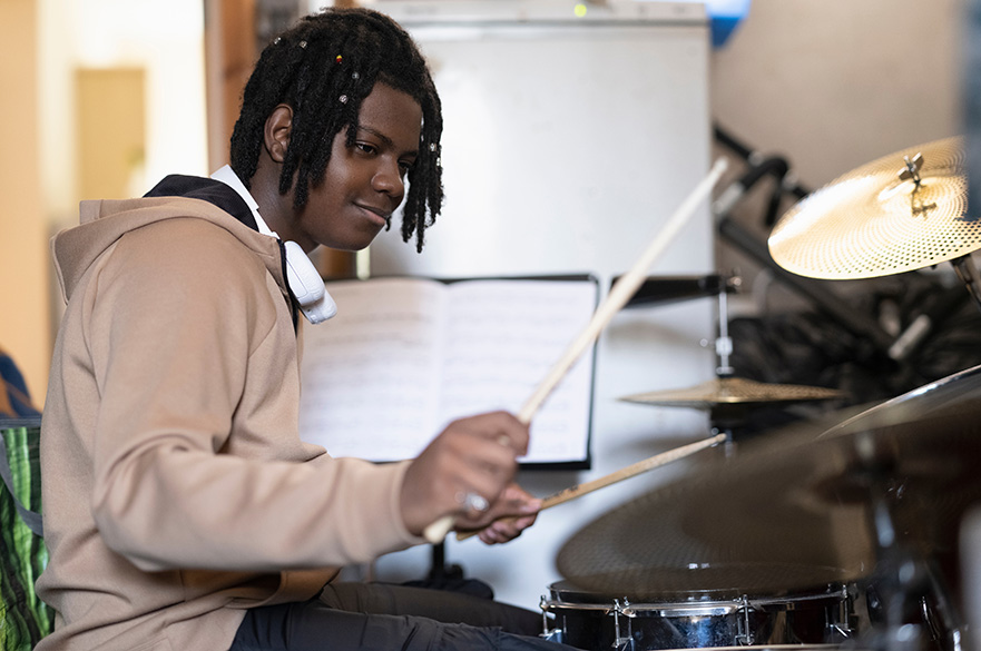A black boy playing the drums.