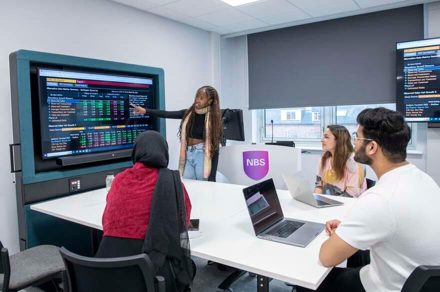 Students in a classroom looking at a dataset on a large screen.