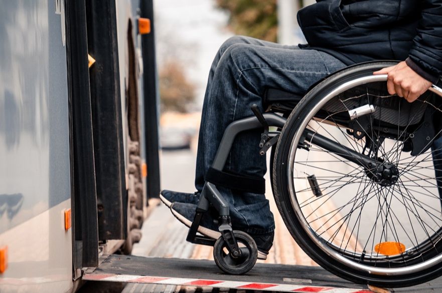 Man in a wheelchair using a ramp to get on a bus