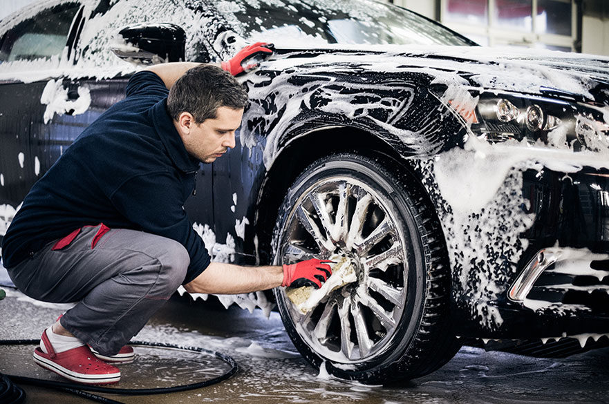 Man hand washing alloy wheels on a car