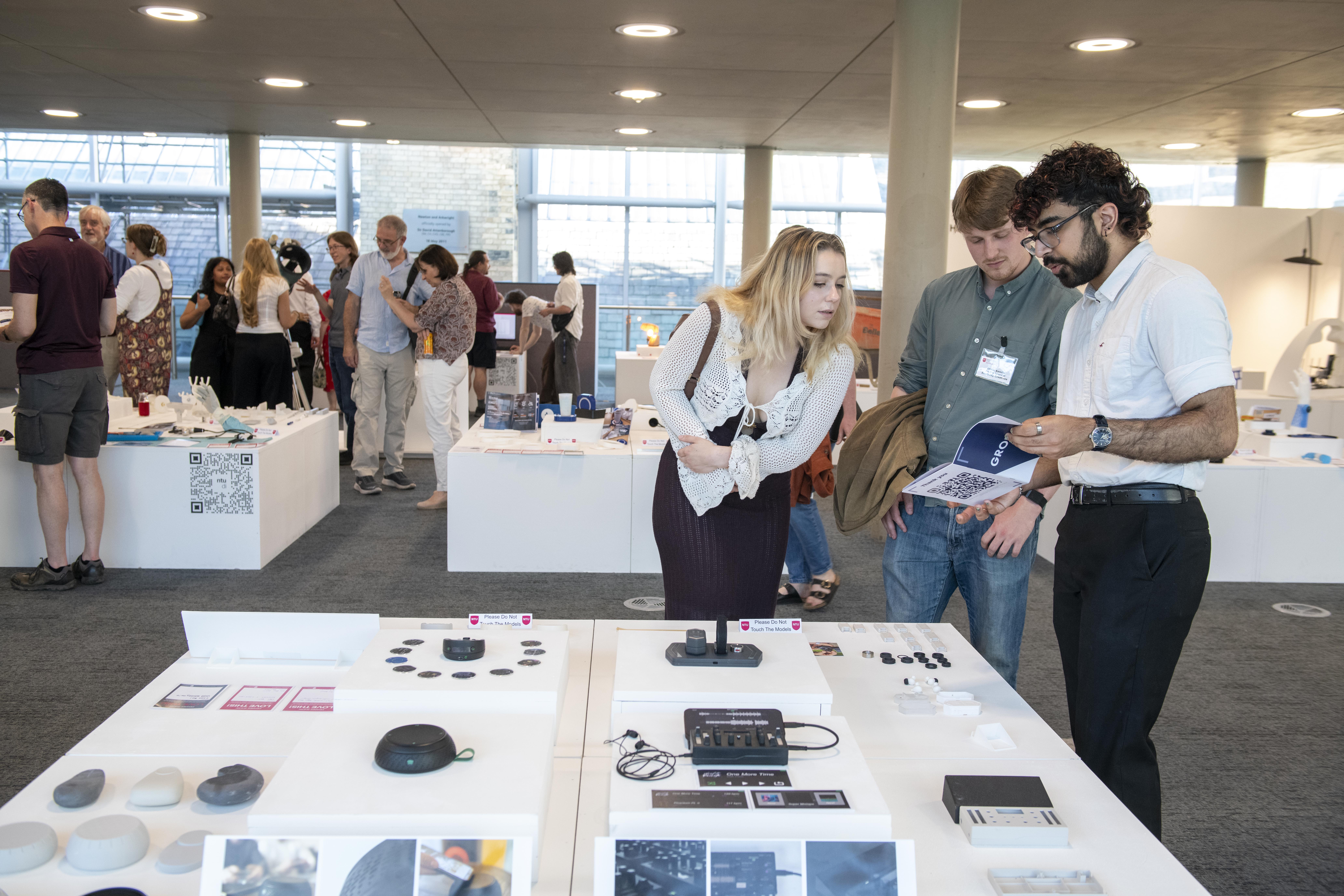 People looking at student project work at an NTU degree show.