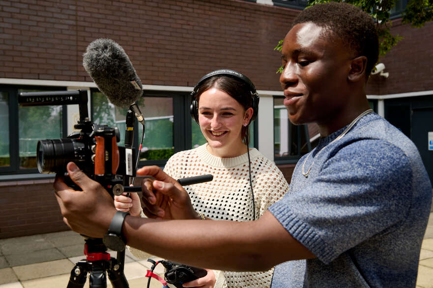 Two students using filming equipment