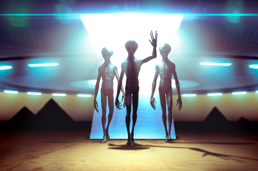 Depiction of three aliens outside a flying saucer type space ship