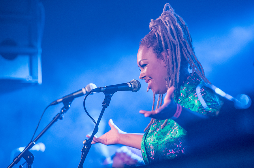 Women with her arms stretched out stood at a microphone.