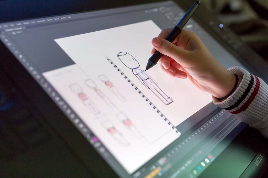 A hand draws an illustration on a tablet.