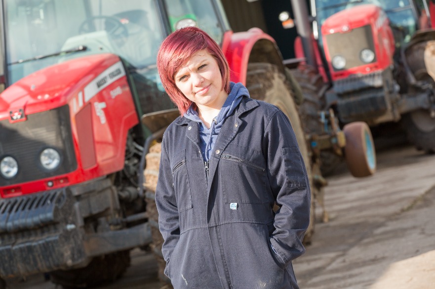 Student standing in front of tractor