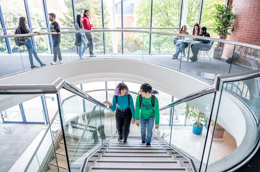 Two students walking up the stairs in the Global Lounge.
