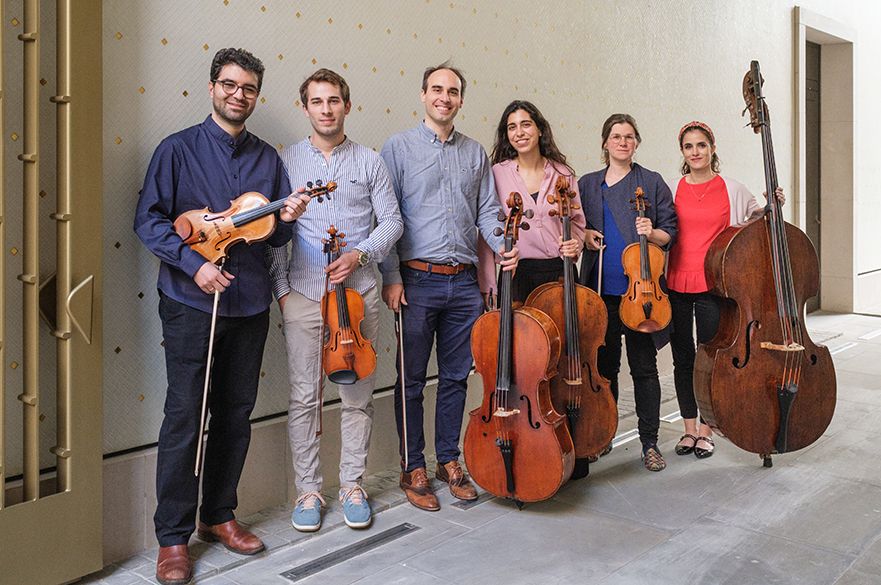 A group of six musicians stood holding their string instruments.
