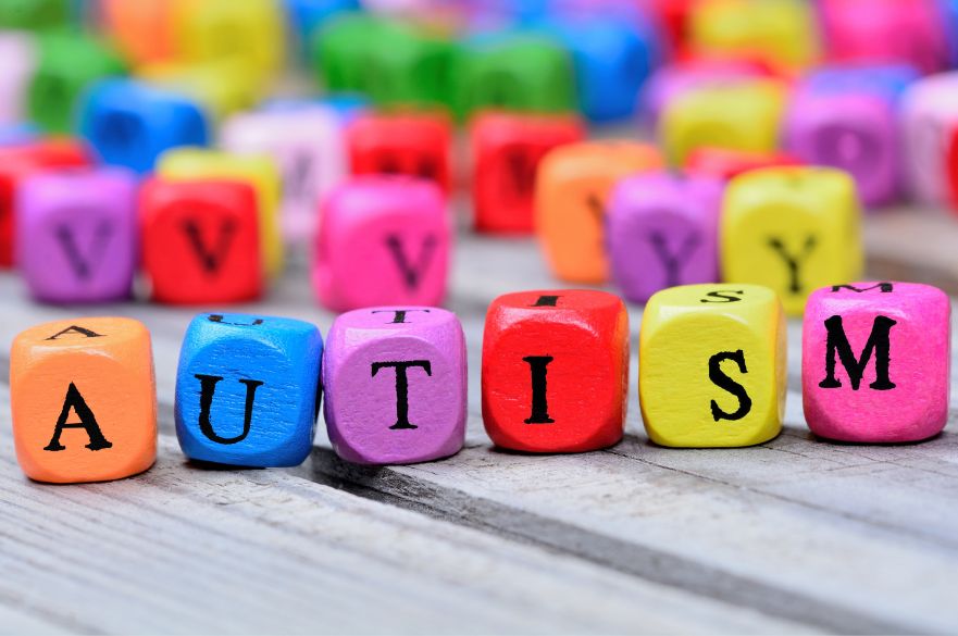 Bright coloured letter blocks on a table spelling out the word autism